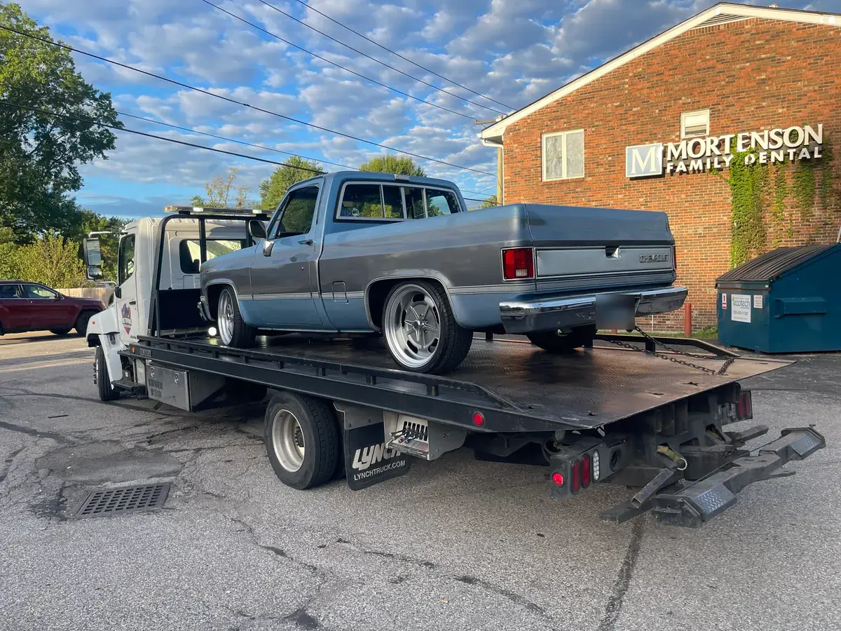 Joe Towing flatbed carrying a grey classic pickup truck.